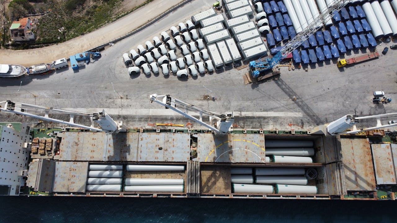 Aerial shot of a port in Lavrio, Greece, showcasing shipping and wind turbine components.